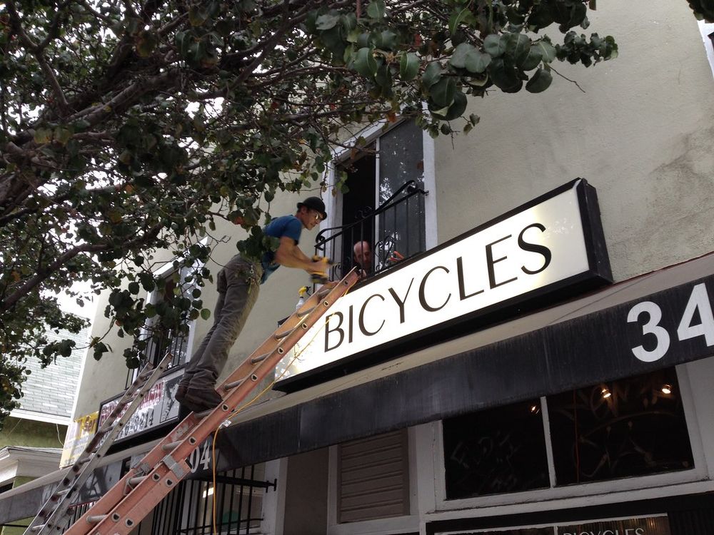An illuminated shop sign being installed on a building